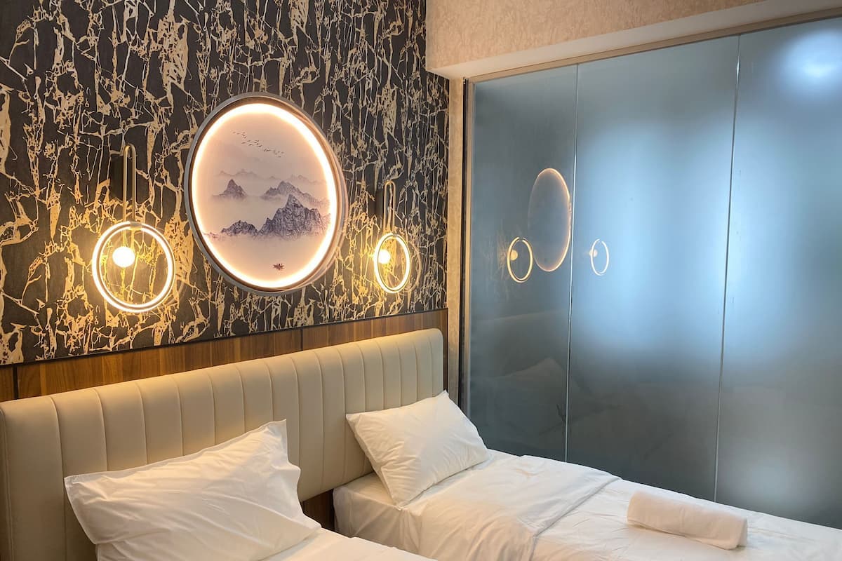 A modern bedroom with a bed, two bedside tables, and a wall with circular light fixtures.