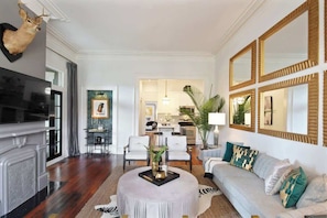 A living room with a fireplace, a television, a sofa, and a dining area with chairs.