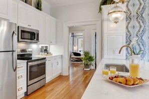 A modern kitchen with stainless steel appliances, white cabinetry, and a wooden floor.