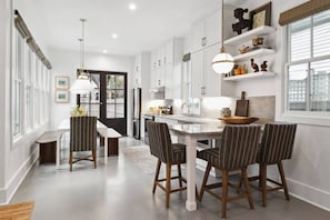 A modern kitchen with white cabinets, a central island, and striped chairs.