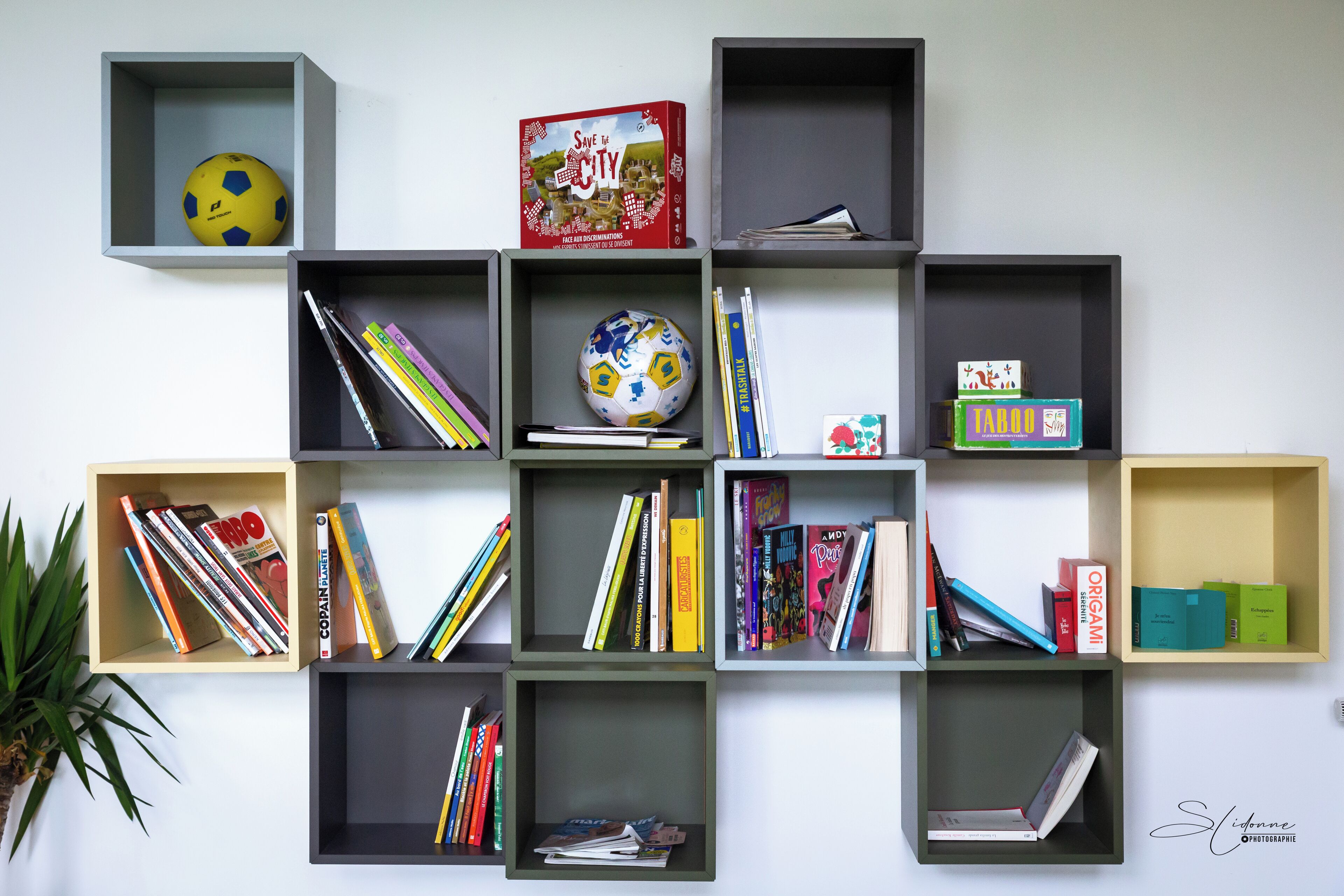 A wall with multiple open shelves containing books, a soccer ball, and a book titled "Save the City".