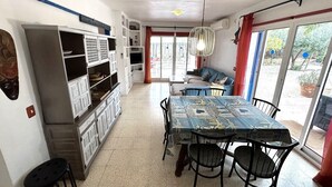 Un coin repas comprenant une table et des chaises, un meuble encastré et une vue sur l’extérieur, accessible par une porte vitrée.