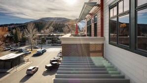 A hotel with a staircase leading to a second-floor balcony overlooking a parking lot and a mountainous landscape.