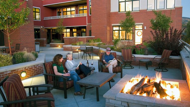 An outdoor patio with brick walls, seating, and a fire pit.