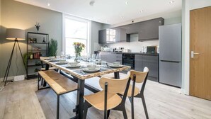 A modern kitchen with a dining table set for four, a built-in oven, and a refrigerator.