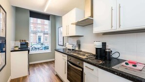 A modern kitchen with white cabinets, a black countertop, and a window with a view of a building outside.