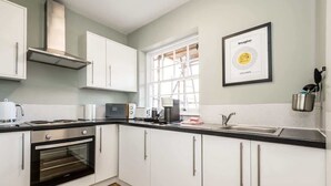 A modern kitchen with white cabinets, a built-in oven, a microwave, and a large window. - Host & Stay | Catharine Quarters I (Liverpool)
