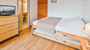 A bedroom with a wooden bed, a television on a wooden dresser, and a wooden ceiling. - Cozy Studio with Wi-Fi, BBQ, Summer Pool, Near Ski Pistes & Free Village Shuttle (Saint-Chaffrey)