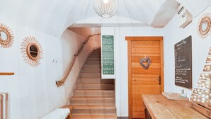 A wooden staircase leading to a room with a heart-shaped decoration on the door, a bench, a table, and a wall with a mirror and a sign. - Cozy Studio with Wi-Fi, BBQ, Summer Pool, Near Ski Pistes & Free Village Shuttle (Saint-Chaffrey)