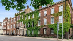 Une rangée de maisons mitoyennes aux façades en briques et recouvertes de lierre vert.