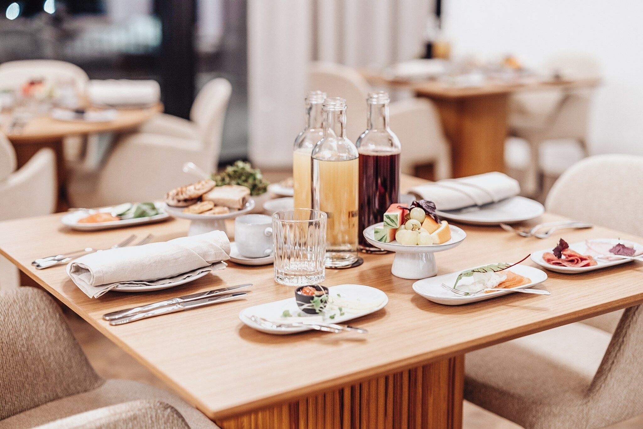 A dining table set with plates of food, glasses, and bottles of beverages.