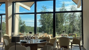 A spacious dining area with large windows, modern furniture, and a view of the outdoors. - PihlasResort (Joroinen)