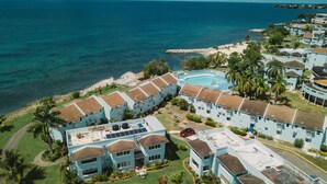 A resort with multiple buildings, a swimming pool, and a view of the ocean. - Palm Point - 2/2 Townhouse Steps from the Beach (Negril)
