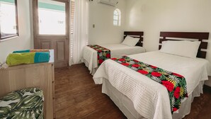 A hotel room with two beds, a wooden dresser, a window with curtains, and an air conditioning unit. - Palm Point - 2/2 Townhouse Steps from the Beach (Negril)