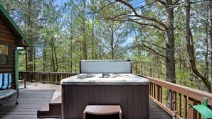 Un bain à remous sur une terrasse en bois, entouré d’arbres.