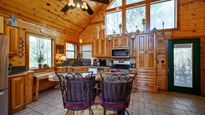 L’intérieur d’un chalet en bois comprend une cuisine, un coin repas et de grandes fenêtres.