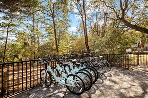 Bicycles are secured to a rack near a wooden structure in a park setting.