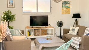 Ein Wohnzimmer mit Fernseher, Sofa, Couchtisch und einer Lampe.