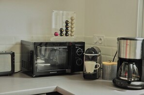 Una cucina con forno a microonde, macchina per il caffè e caraffa da caffè sul piano di lavoro.
