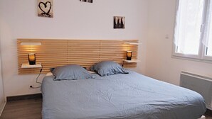 Ein Schlafzimmer mit Bett, Nachttischlampen, einem Kopfteil und Wandbildern.