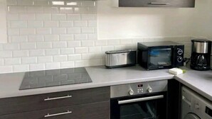 Eine kompakte Küche mit Mikrowelle, Toaster, Kaffeemaschine, Backofen und Geschirrspüler.