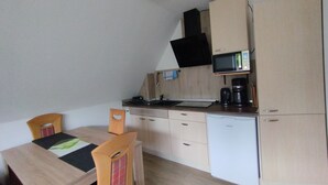 Una cocina compacta con microondas, cafetera y armarios de madera.