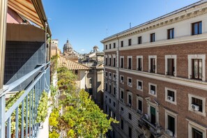 Une rue étroite, bordée de bâtiments de chaque côté, avec des balcons et une vue dégagée sur une structure en forme de dôme au loin.