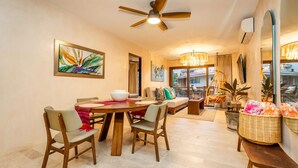 A dining area with a round wooden table, four chairs, a ceiling fan, and artwork on the walls. - Casa Kaia, Ocean-View Boho-Chic, 2bd/2ba Condo in Golden Zone (Bucerías)