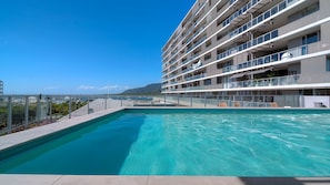 A modern hotel with a rooftop pool, multiple balconies, and a view of the sea. - Belle Escapes - 405 Harbour Lights (Cairns City)