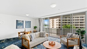 A modern living room with a sofa, two armchairs, a coffee table, and artwork on the walls. - Belle Escapes - 405 Harbour Lights (Cairns City)