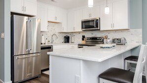 Una cocina moderna con armarios blancos, electrodomésticos de acero inoxidable y una isla central.