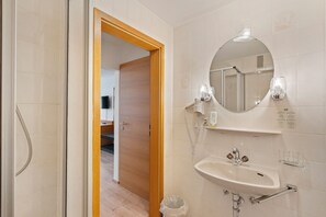 Un baño con puerta de madera, un lavabo con espejo y una cabina de ducha de vidrio.