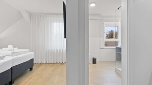 A modern hotel room with a bed, a window with curtains, and a view of the outside. - Hotel Garni Traube (Friedrichshafen)