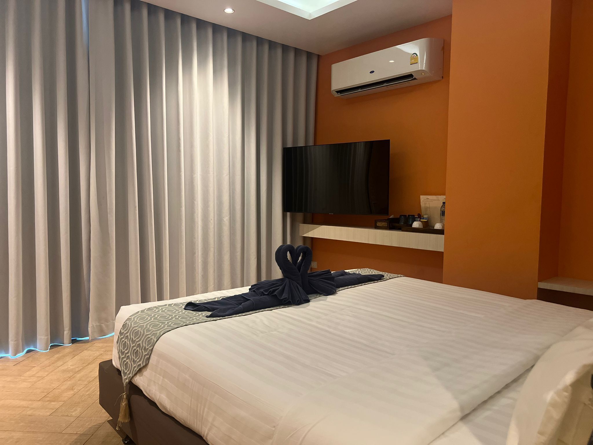 Habitación de hotel con cama, televisión de pantalla plana, aire acondicionado y ventana con cortinas.