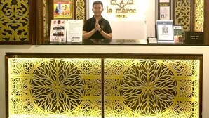 Una reception d'albergo con decorazioni dorate elaborate, un logo e una targa con il nome.