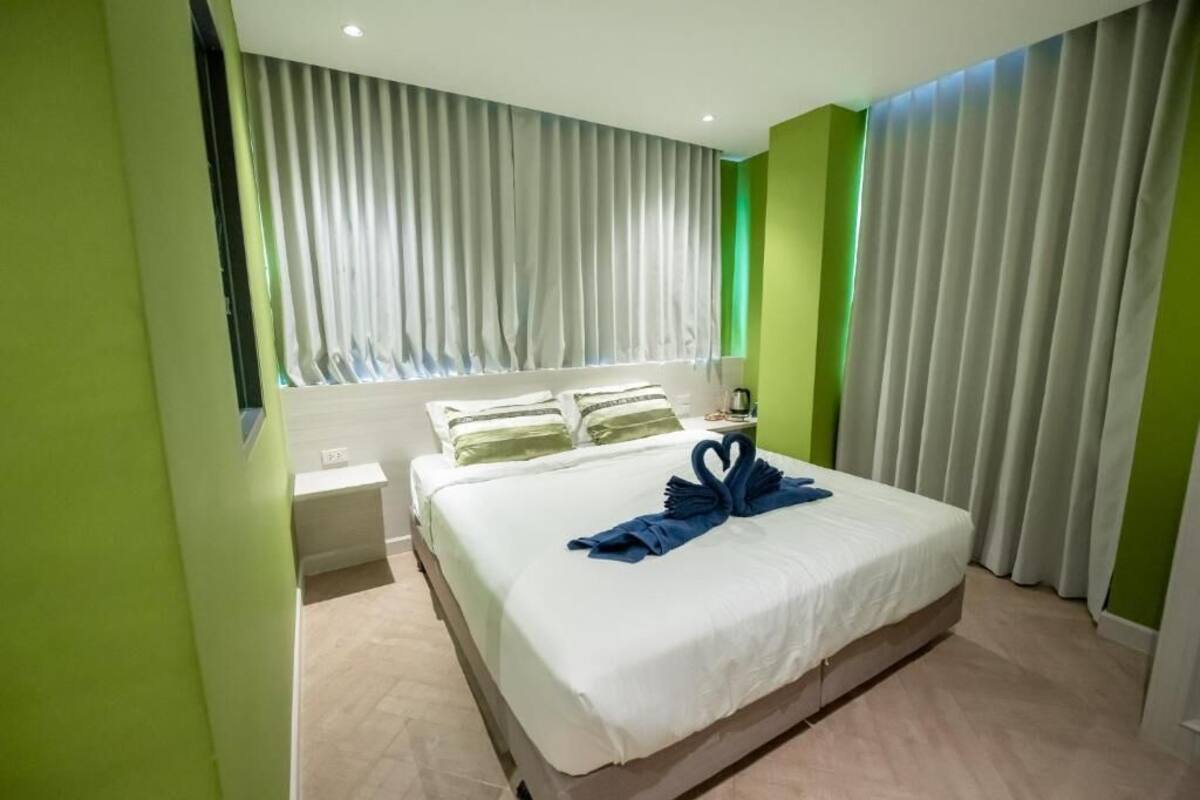 A hotel room with a bed, a nightstand, and a window with curtains.