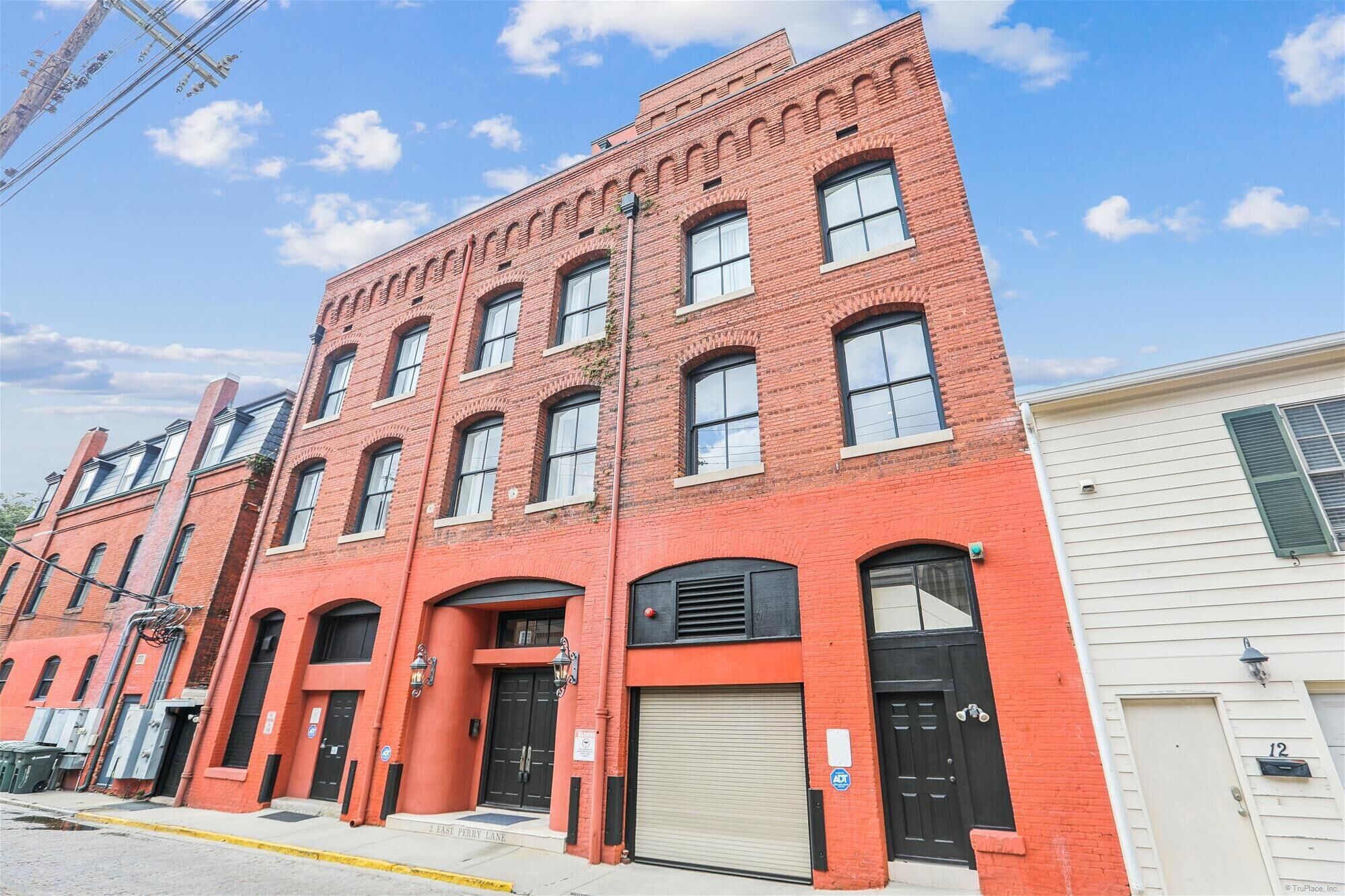 A red brick building with multiple windows and a garage door, located at 2 East Perry Lane.