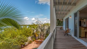 A wooden deck with outdoor furniture, a pool, and lush greenery. - Coastal Comfort & 3/4 Time Compound (Key West)