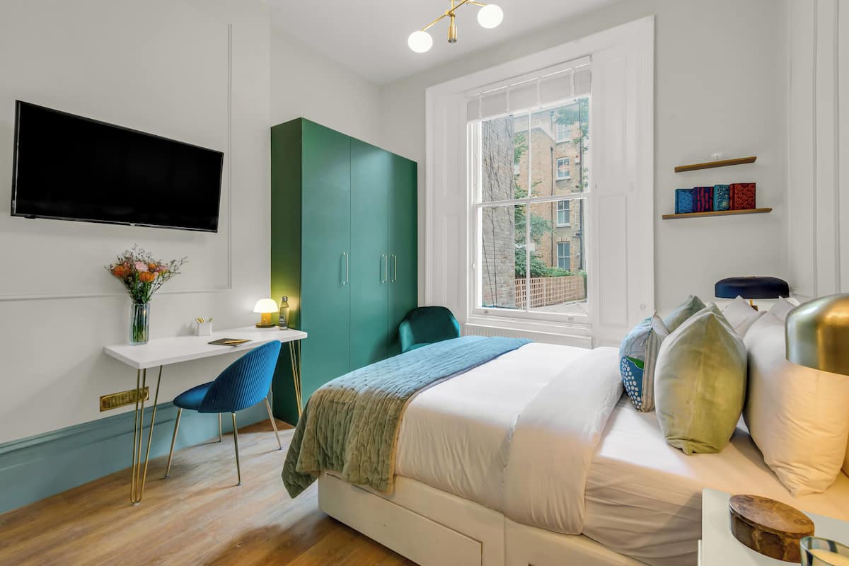 A modern bedroom with a bed, a desk, and a TV.
