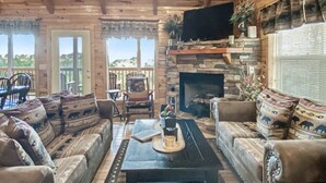 A cozy living room with a fireplace, wooden ceiling, and comfortable seating.