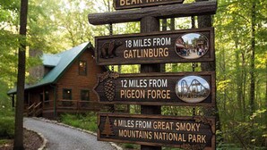 A wooden signpost with distance markers to Gatlinburg, Pigeon Forge, and Great Smoky Mountains National Park.