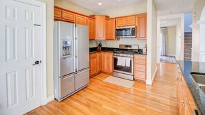 A kitchen with wooden cabinets, a stainless steel refrigerator, a microwave, and a stove. - Convenient | 2 King Beds l Fast Wifi (Norfolk)