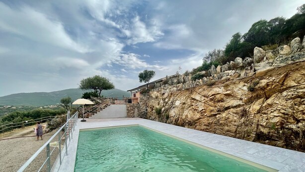 A swimming pool with a stone wall and a staircase leading to a house. - Villa Fiori with pool by Wonderful Italy (Olbia)