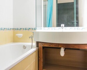A bathroom with a bathtub, a sink, and a mirror.