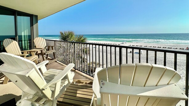 Un balcone con poltrone Adirondack bianche e vista sulla spiaggia.
