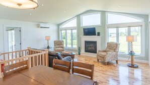 Un amplio salón con chimenea, ventanas grandes y zona de comedor.