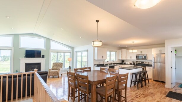 Una cocina amplia con suelo de madera, una zona de comedor con una mesa grande y sillas, y una chimenea.