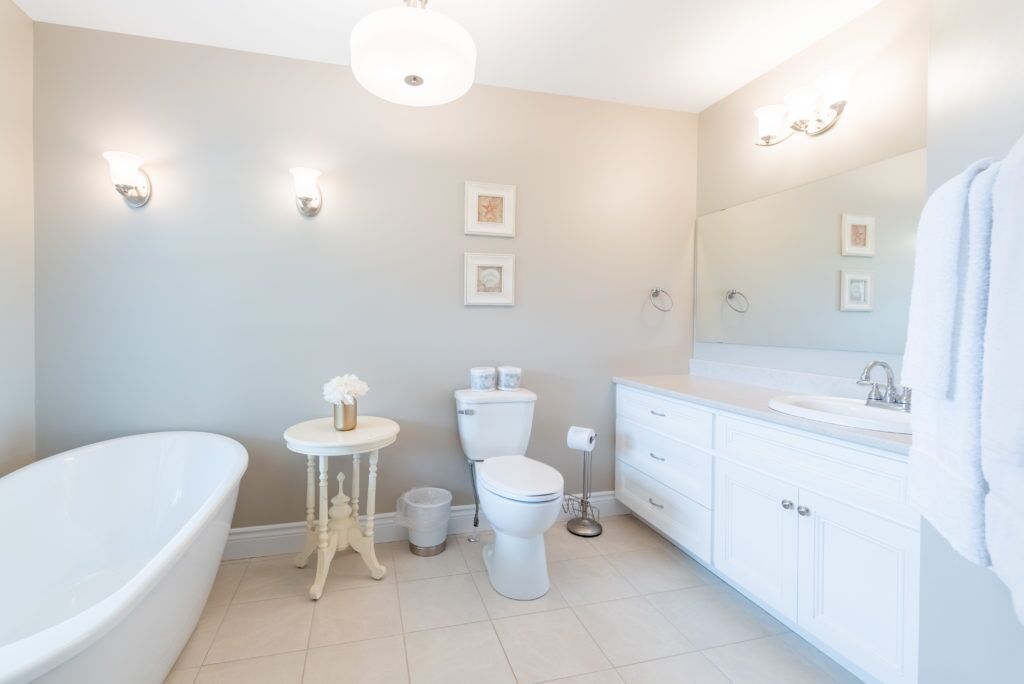 Een badkamer met een vrijstaand bad, toilet, wastafel en een badkamerkast met spiegel.