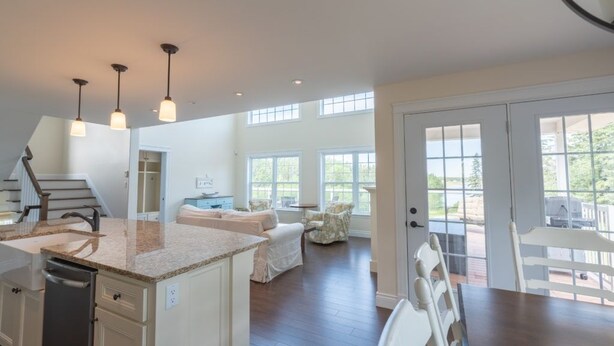 A spacious kitchen with a large island, pendant lights, and a view to the outdoors. - Storybook Island Cottage at The Gables of PEI (Stanley Bridge)