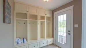 A room with a built-in bench, a door with a window, and a light fixture on the ceiling. - Storybook Island Cottage at The Gables of PEI (Stanley Bridge)
